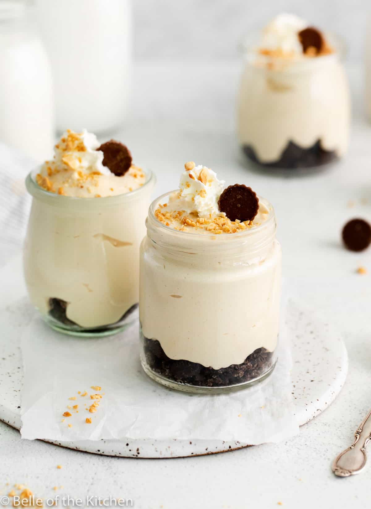 jars of peanut butter mousse topped with whipped cream and peanuts.