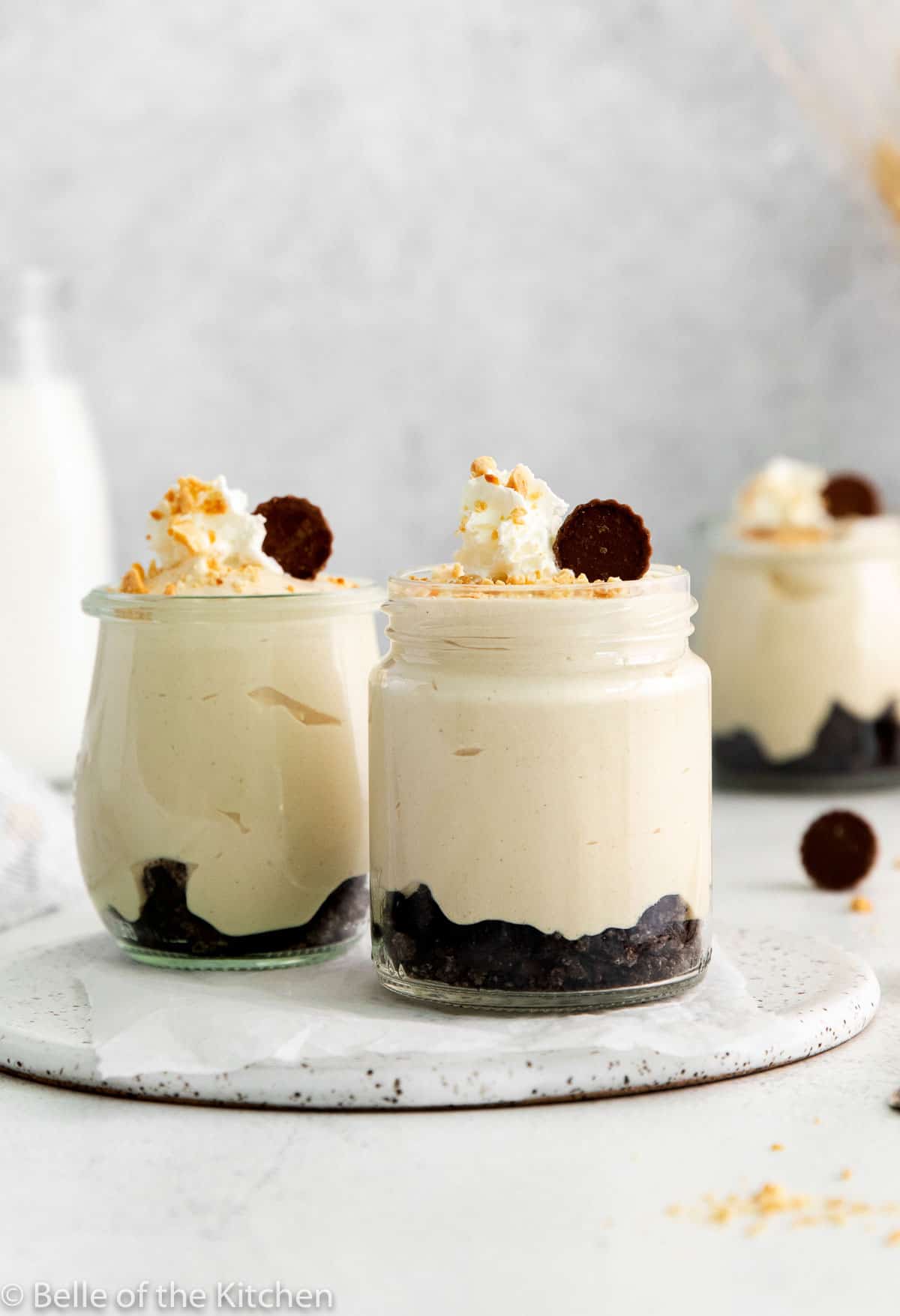 jars of peanut butter mousse topped with whipped cream and peanuts.