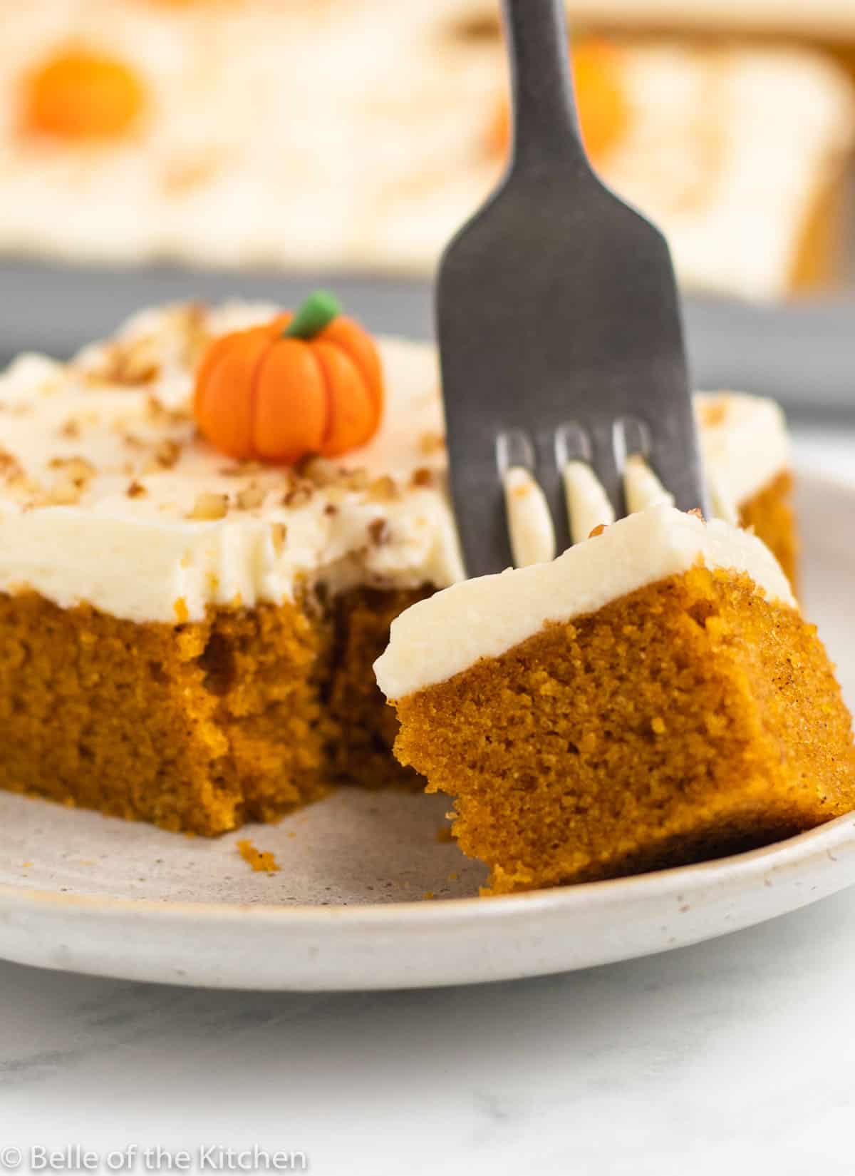 a fork taking a bite out of pumpkin cake on a plate.