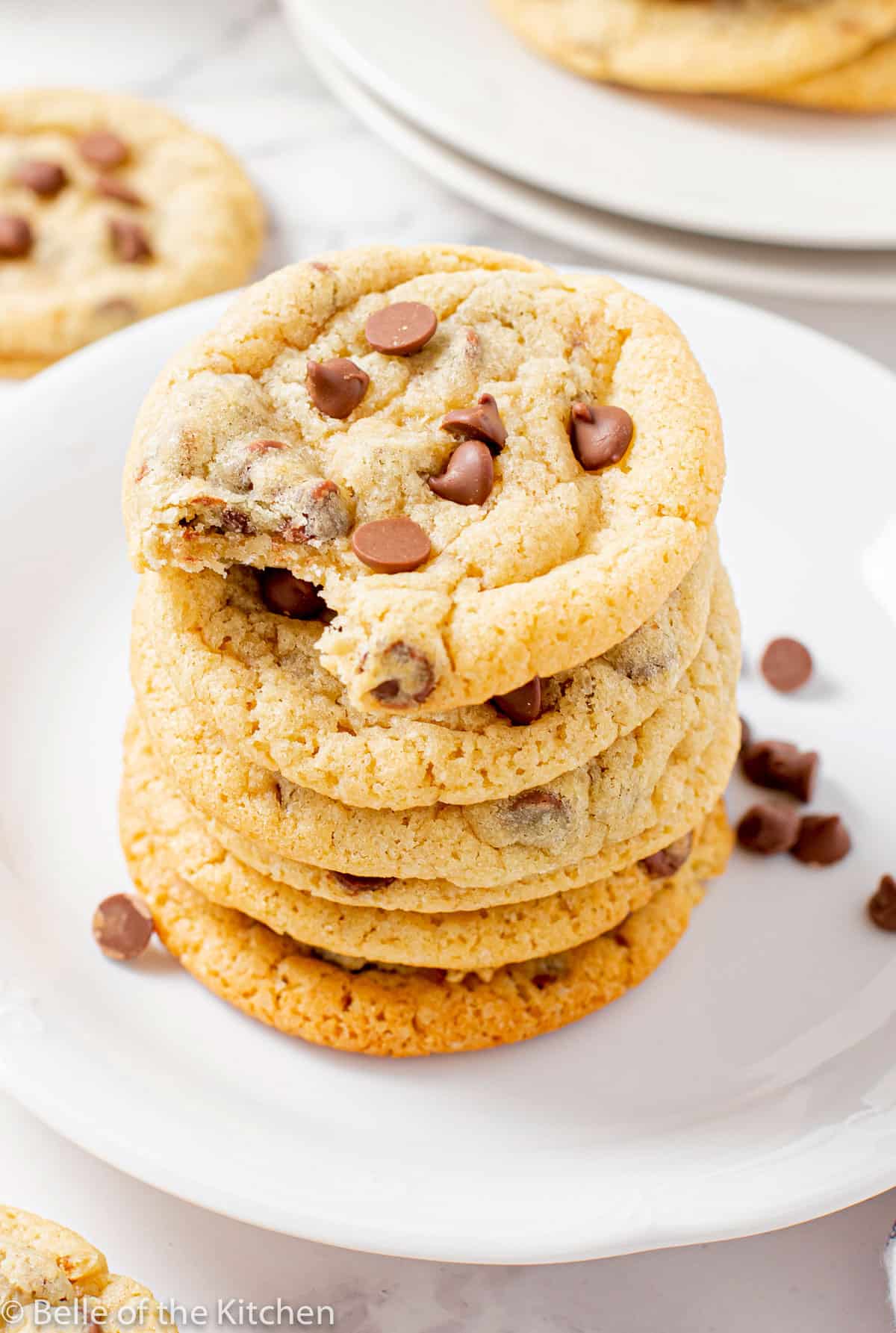 a stack of chocolate chip cookies on a white plate.