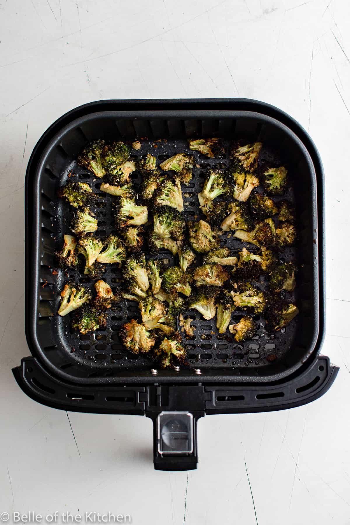 an air fryer basket fall of broccoli.