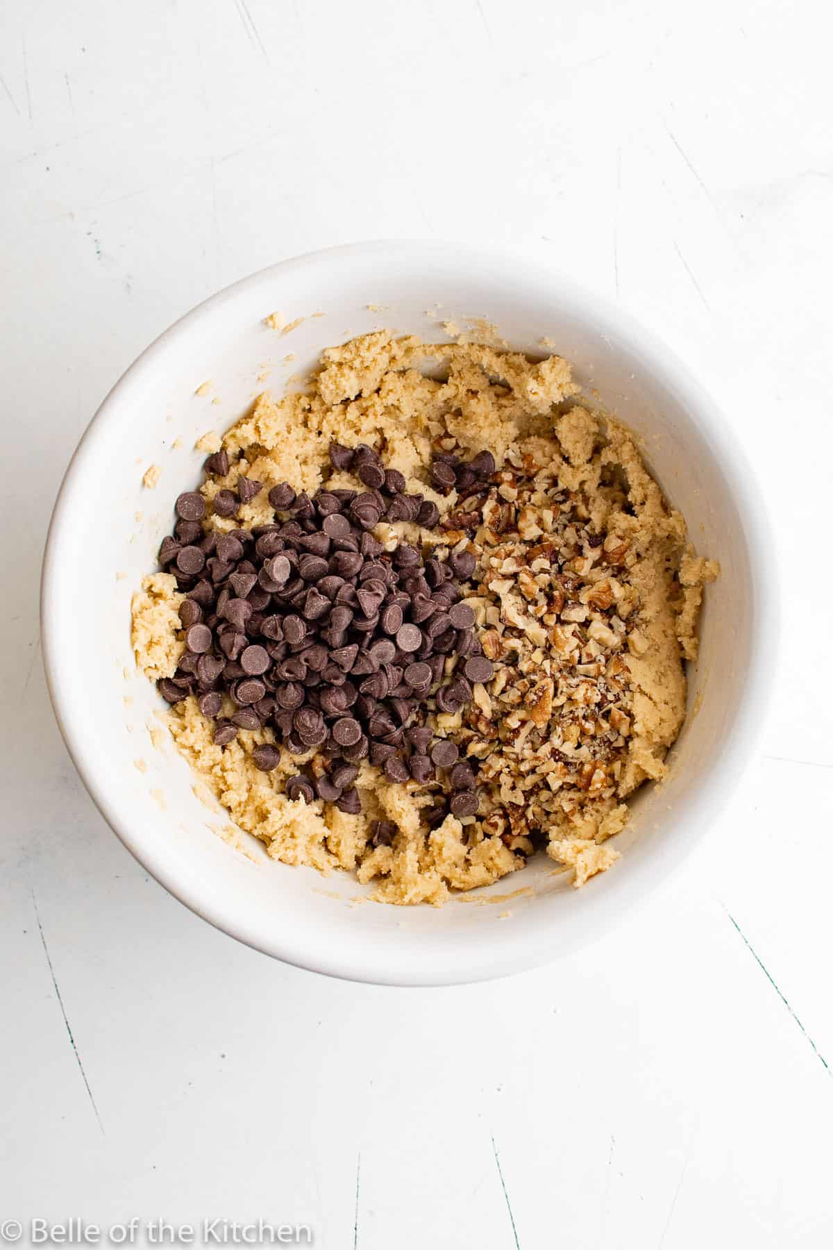 a bowl of dough with chocolate chips and walnuts.