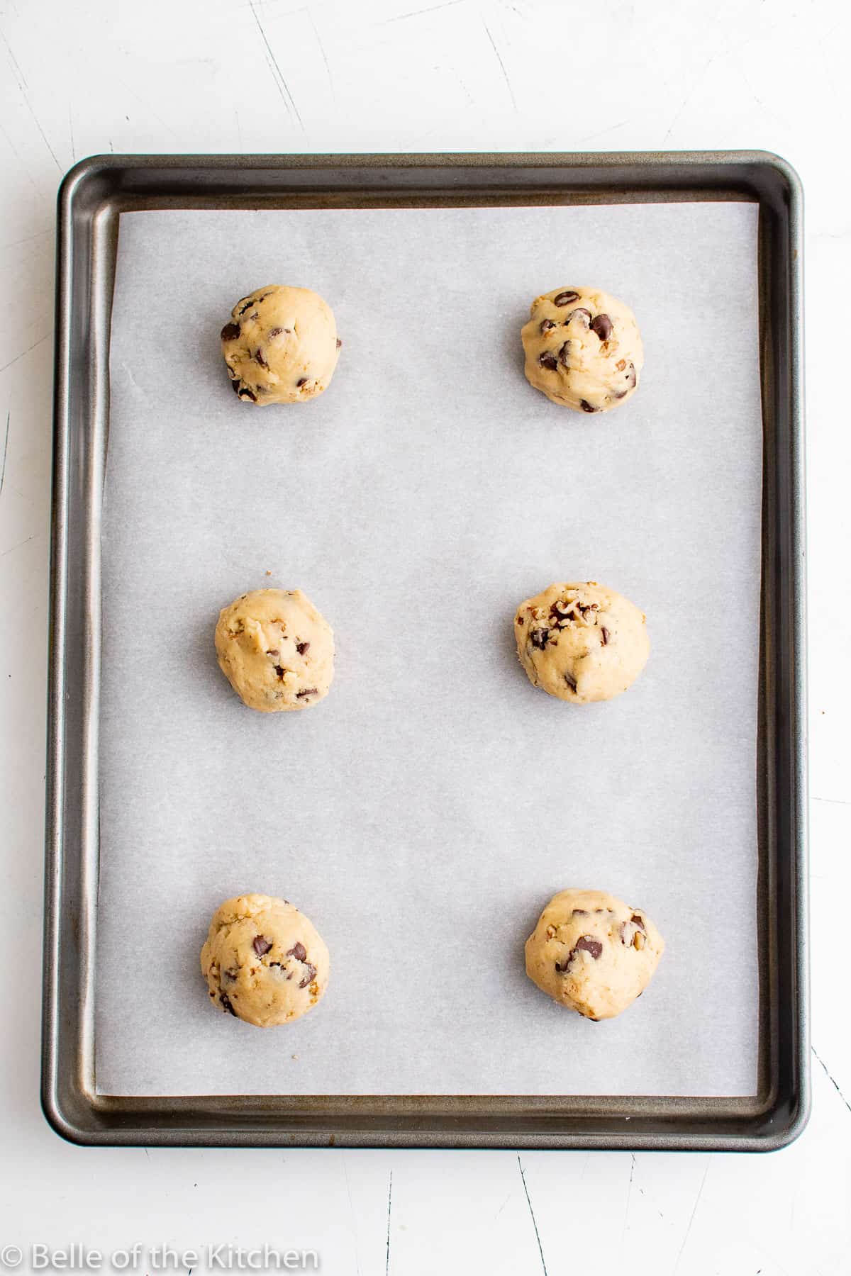 a sheet pan with cookie dough balls on top.