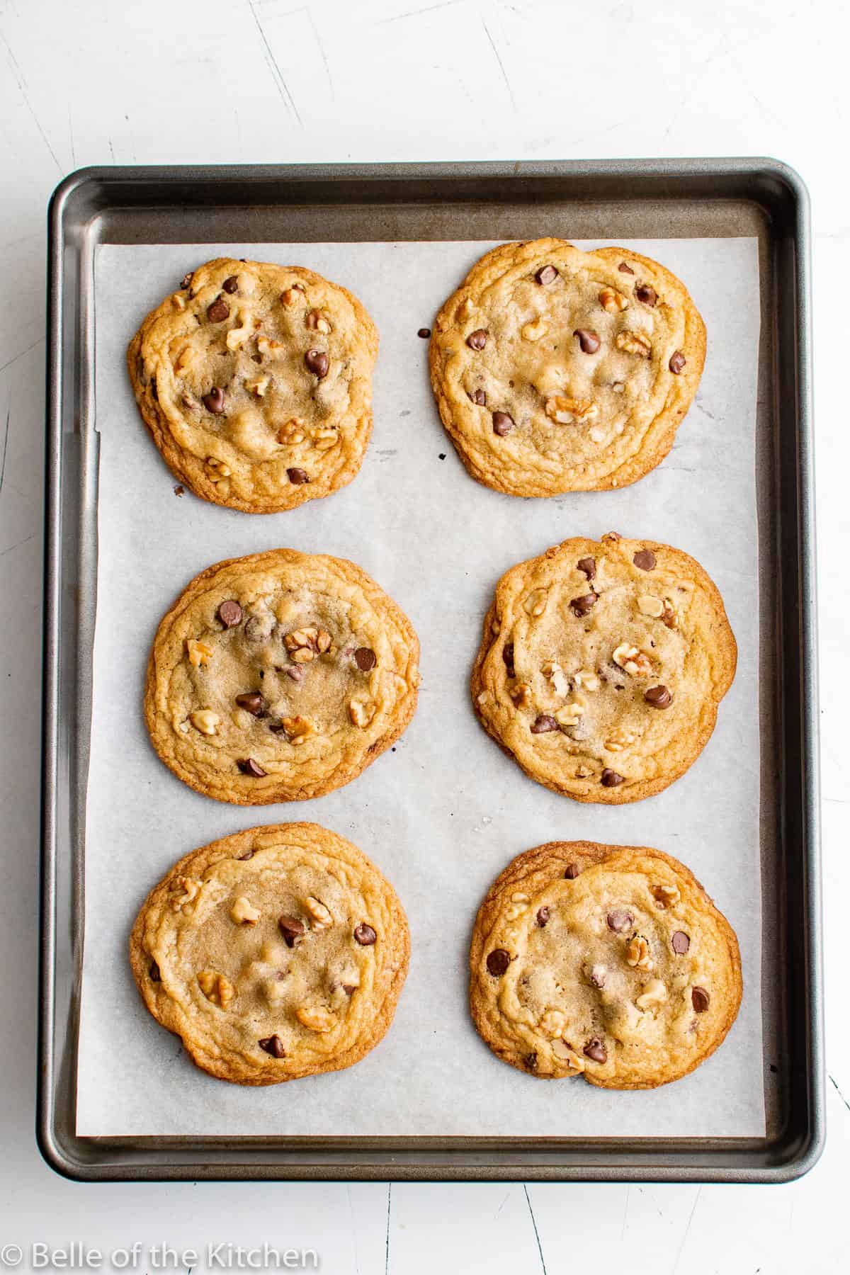 baked chocolate chip walnut cookies on a sheet pan.