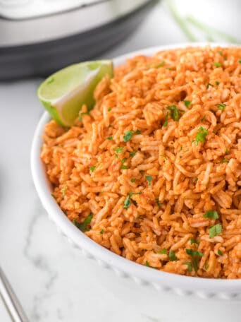 a bowl full of rice with a lime slice on the side.