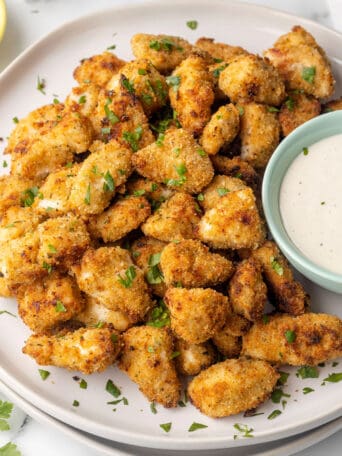 chicken nuggets on a plate next to a bowl of ranch.
