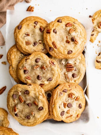 pecan chocolate chip cookies stacked on a wire rack.