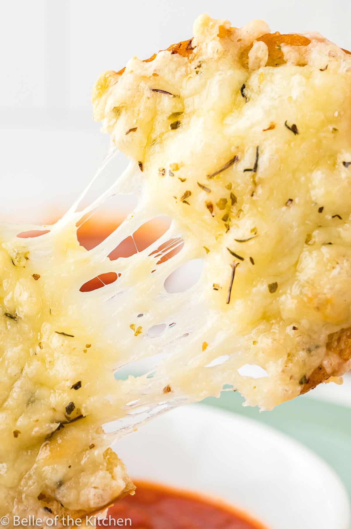 a piece of garlic bread being pulled apart.
