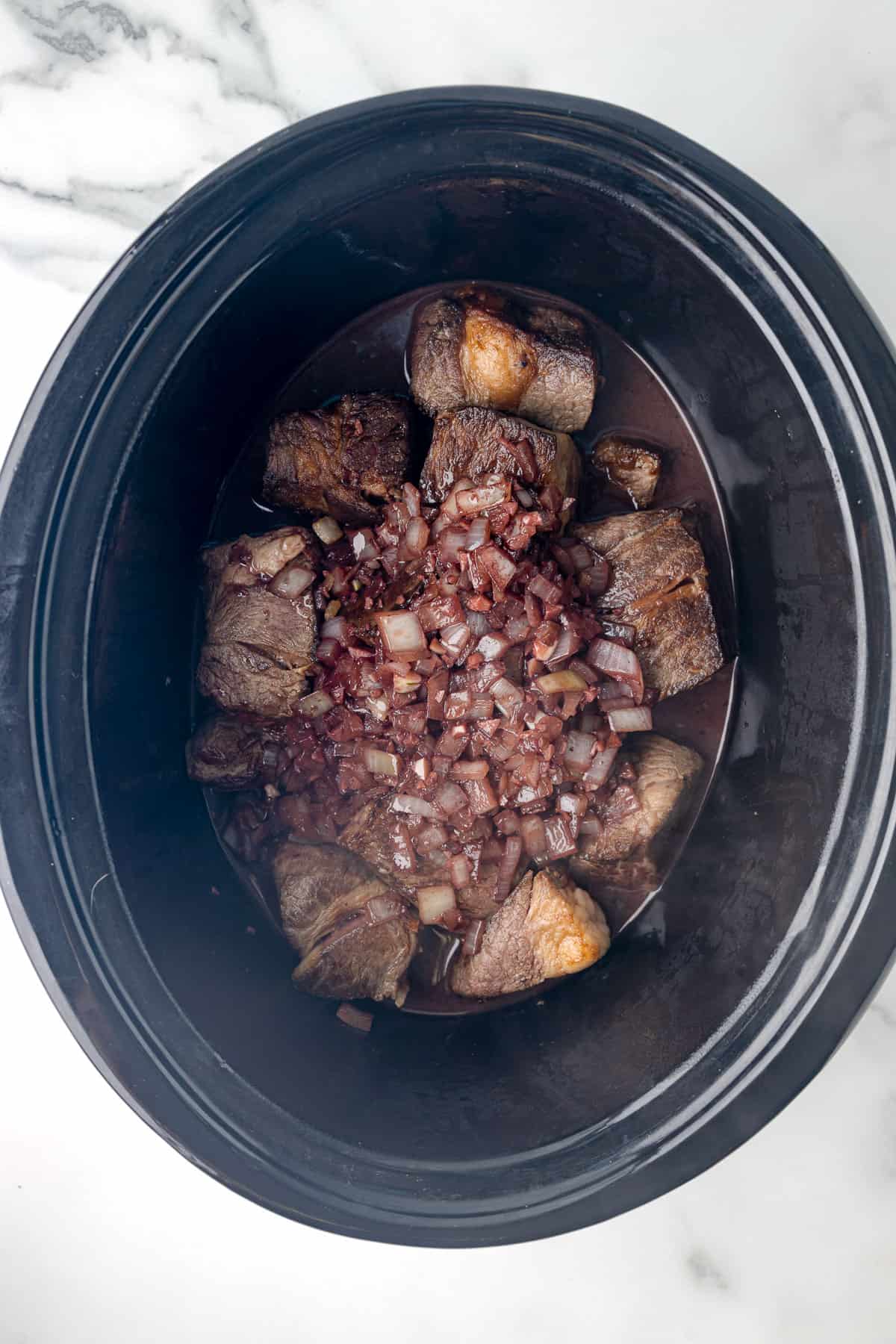 beef, onions, and spices in a crockpot.