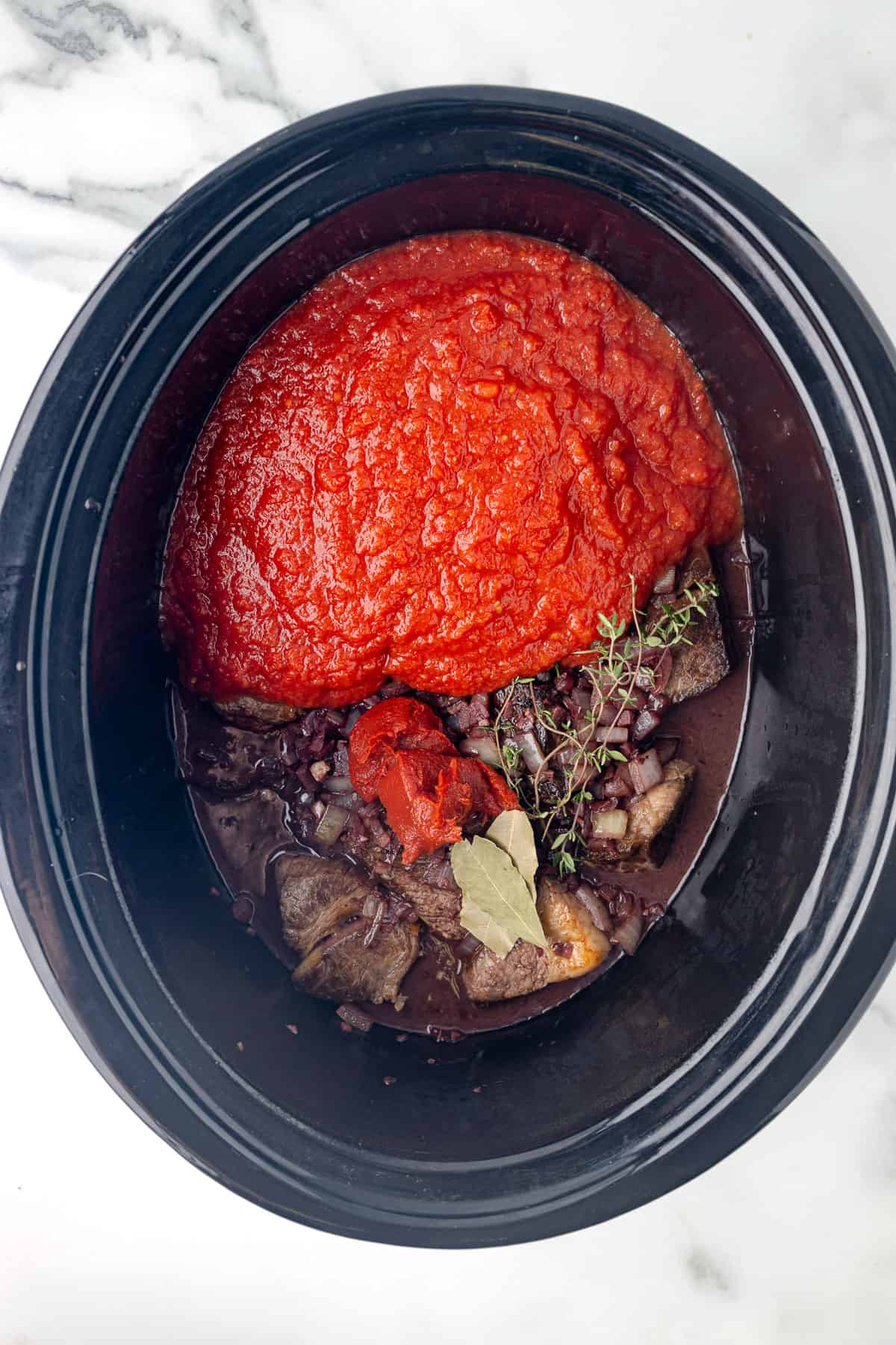 beef, tomatoes, onions, and spices, in a crockpot.