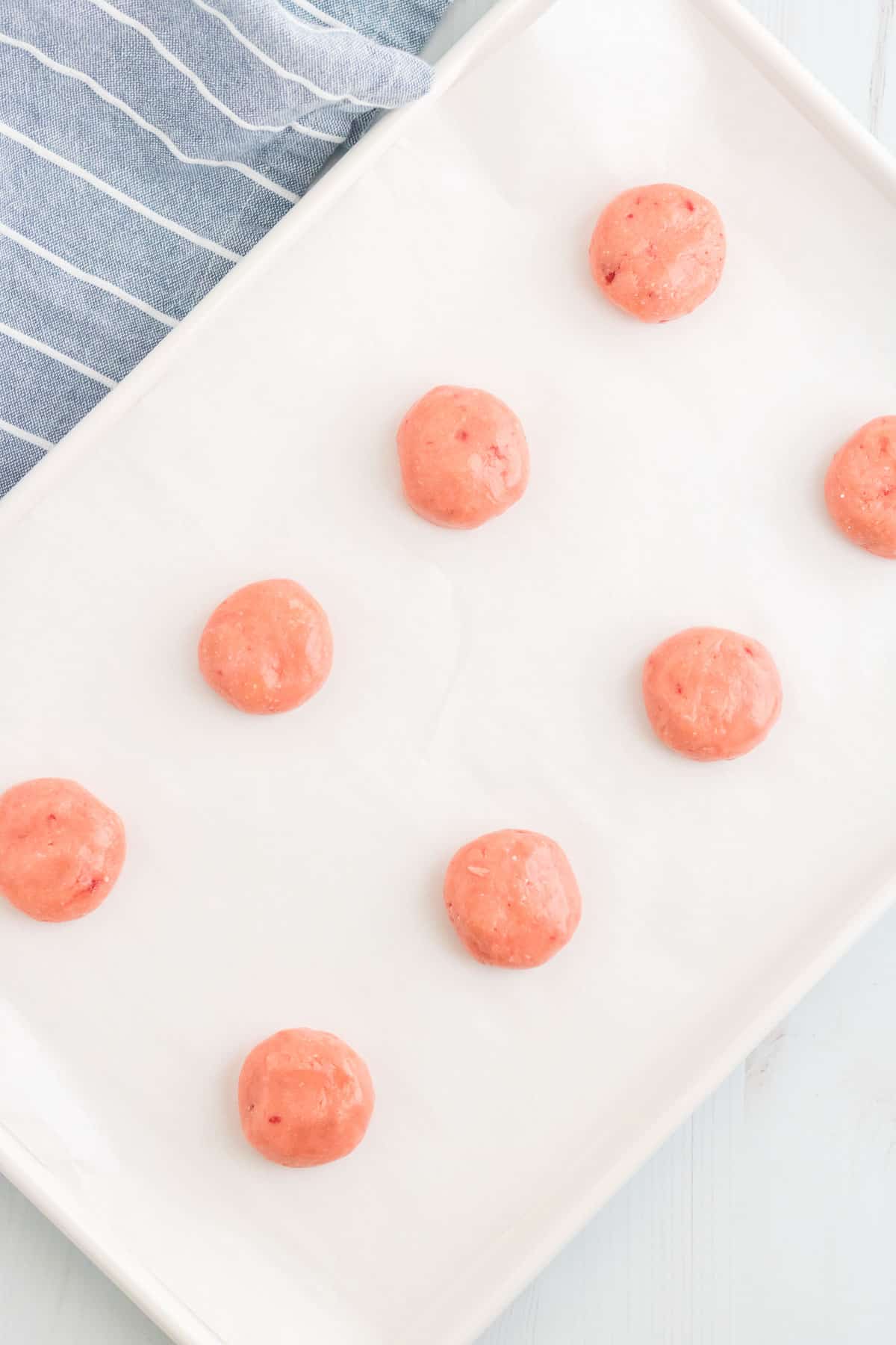 strawberry cookie dough balls on a cookie sheet.