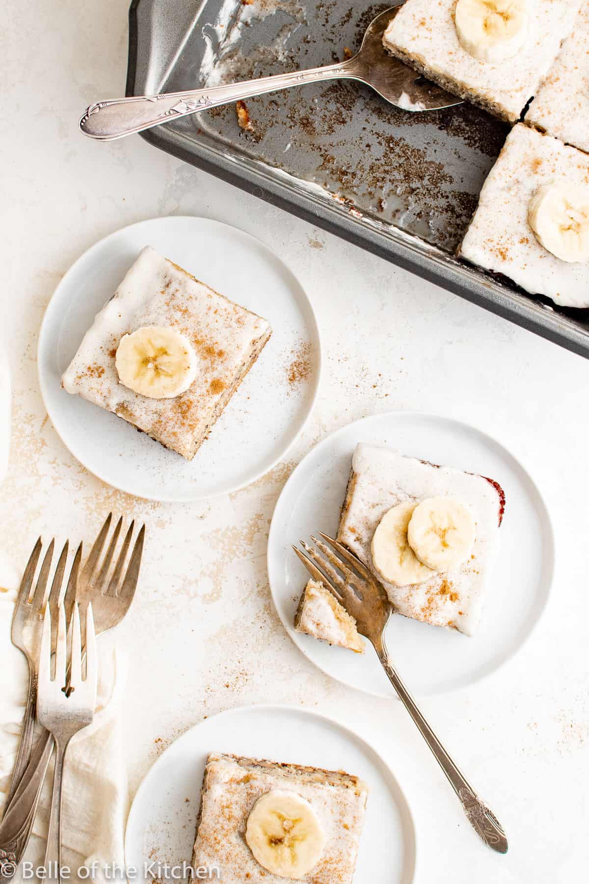 slices of cake topped with sliced bananas on white plates.