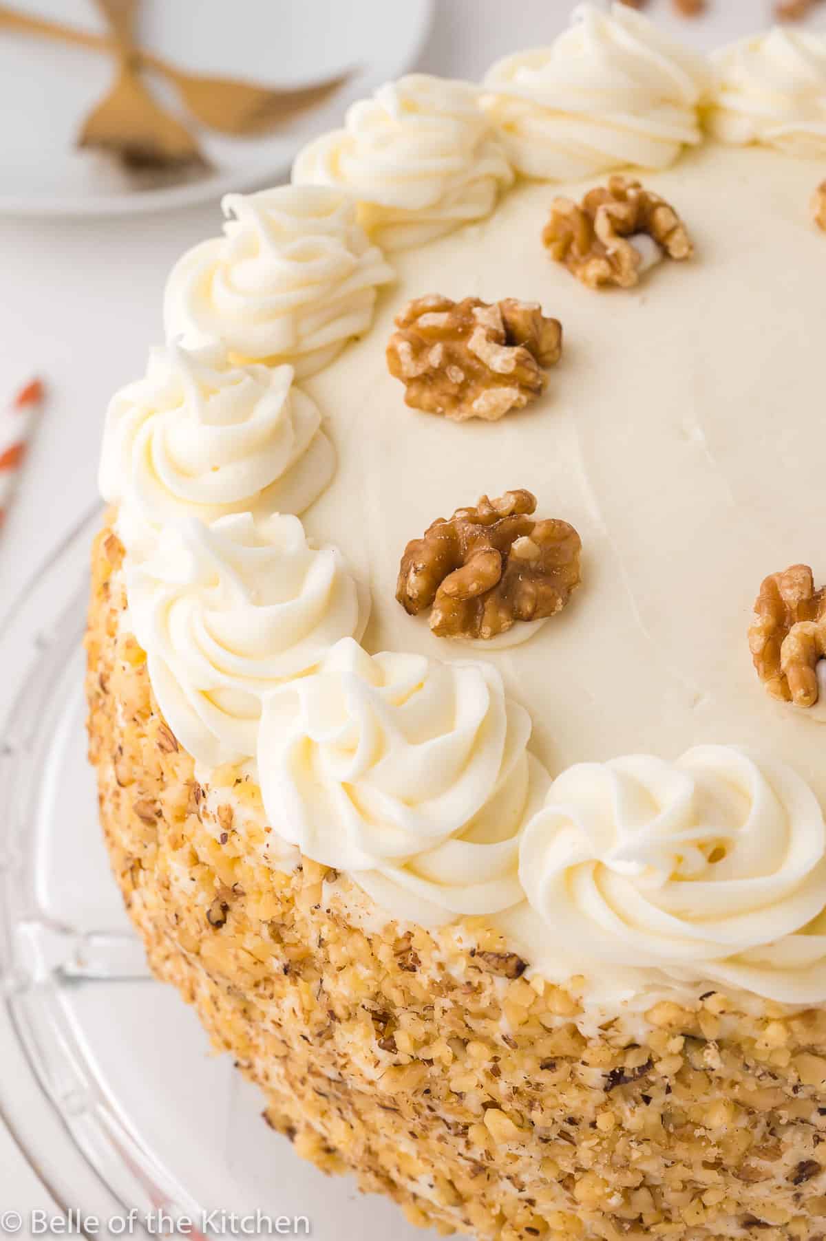 a layered cake with white frosting and walnuts on top.