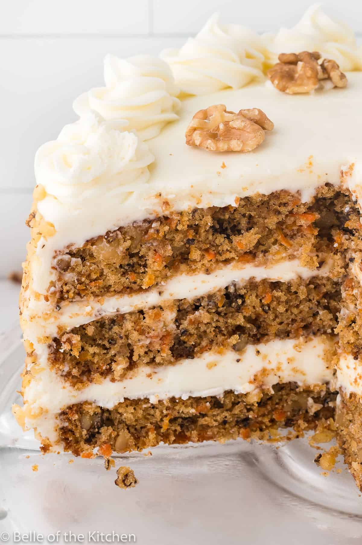 a layered cake with white frosting and walnuts on top.