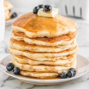 a stack of pancakes topped with butter, syrup, and blueberries.