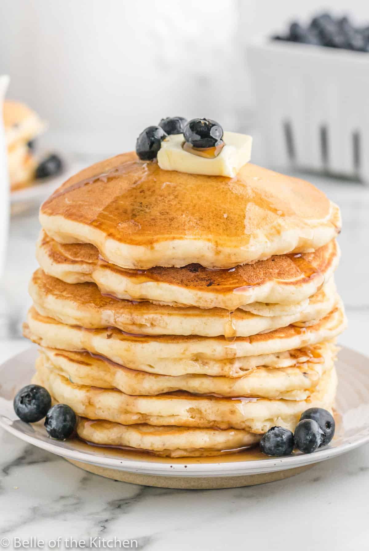a stack of pancakes topped with butter, syrup, and blueberries.