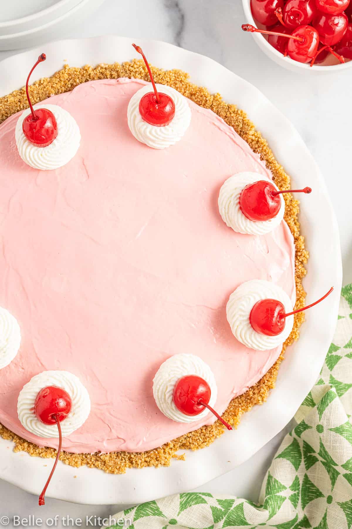 overhead shot of a pink kool aid pie with whipped cream and cherries on top.