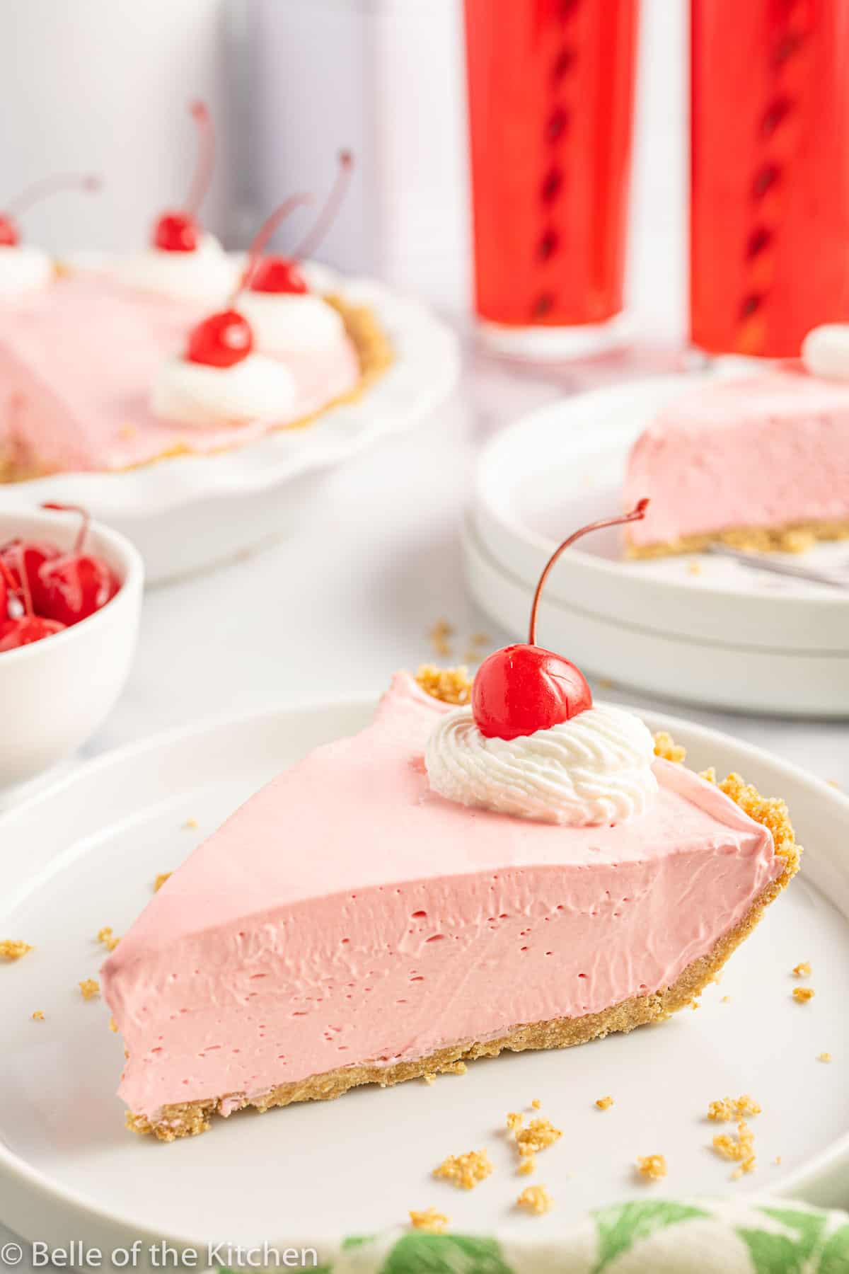 a slice of pink Kool Aid pie on a white plate with a cherry on top.