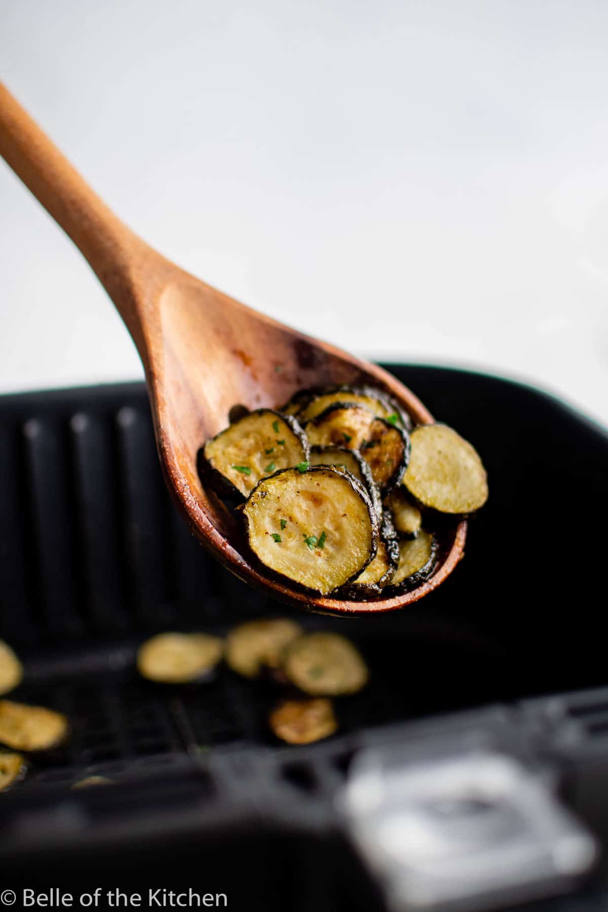 a wooden spoon holding roasted zucchini.