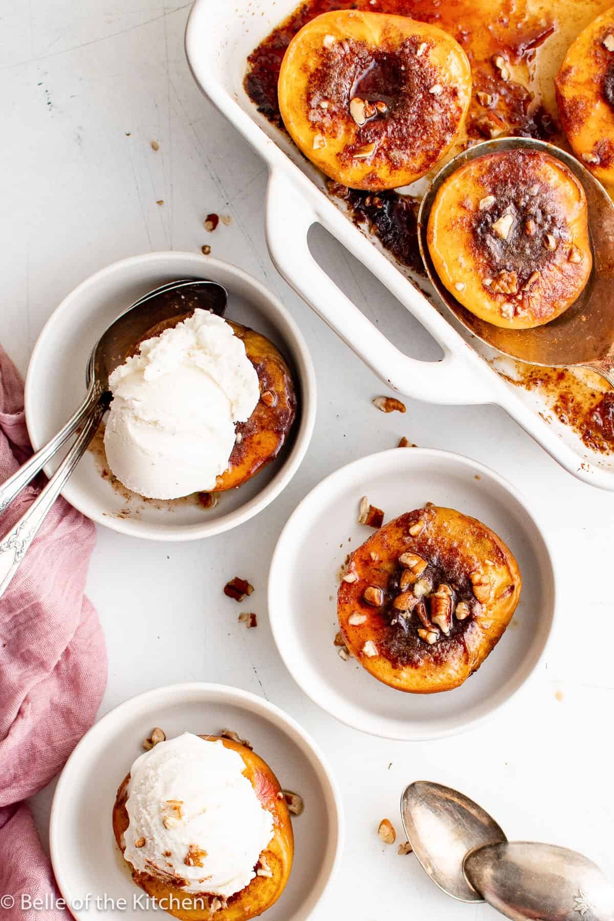 bowls of baked peaches next to a baking dish.