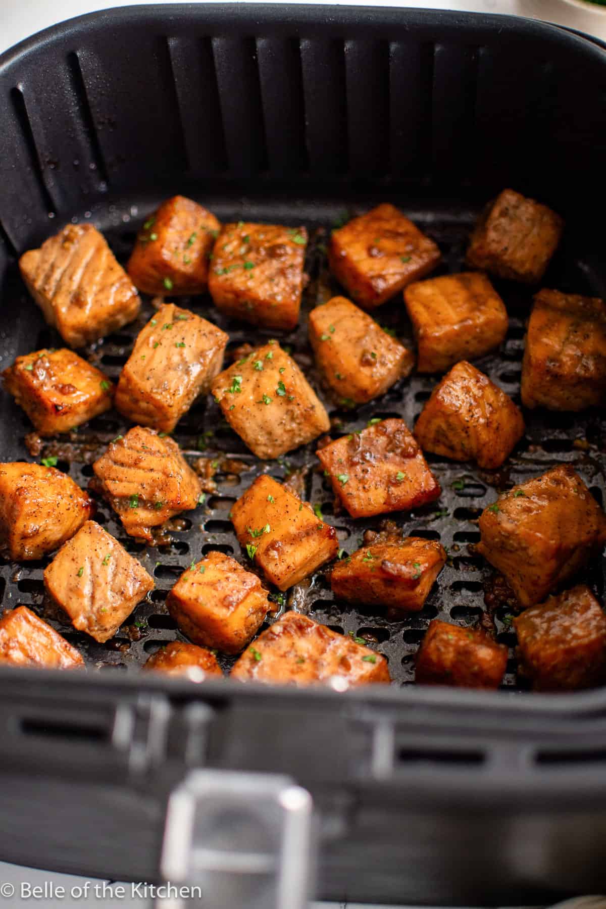 an air fryer basket full of cooked salmon chunks.