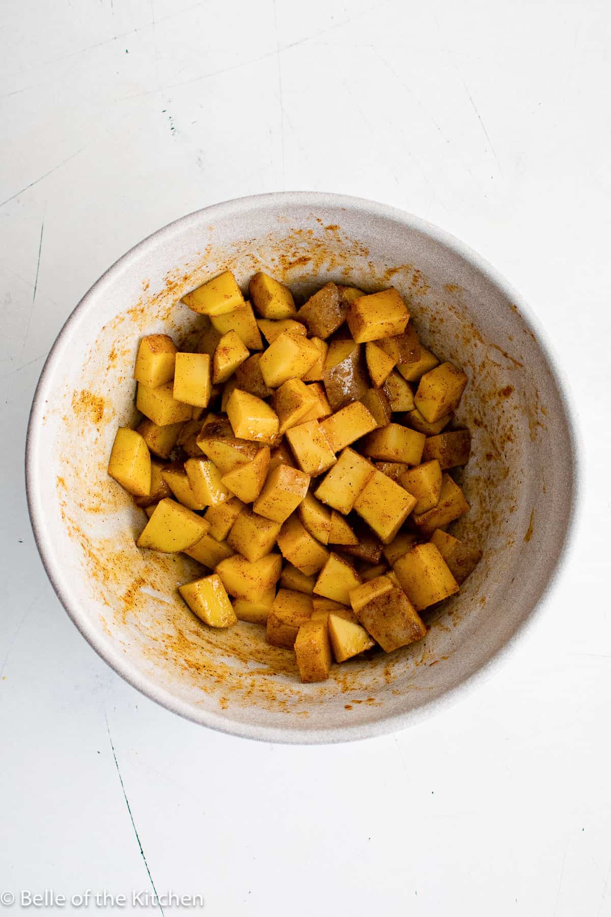 diced potatoes and spices in a white bowl.