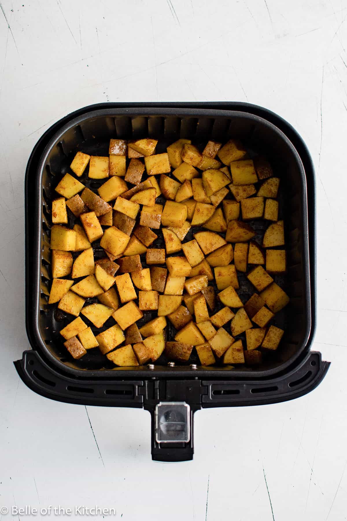 diced potatoes in an air fryer basket.