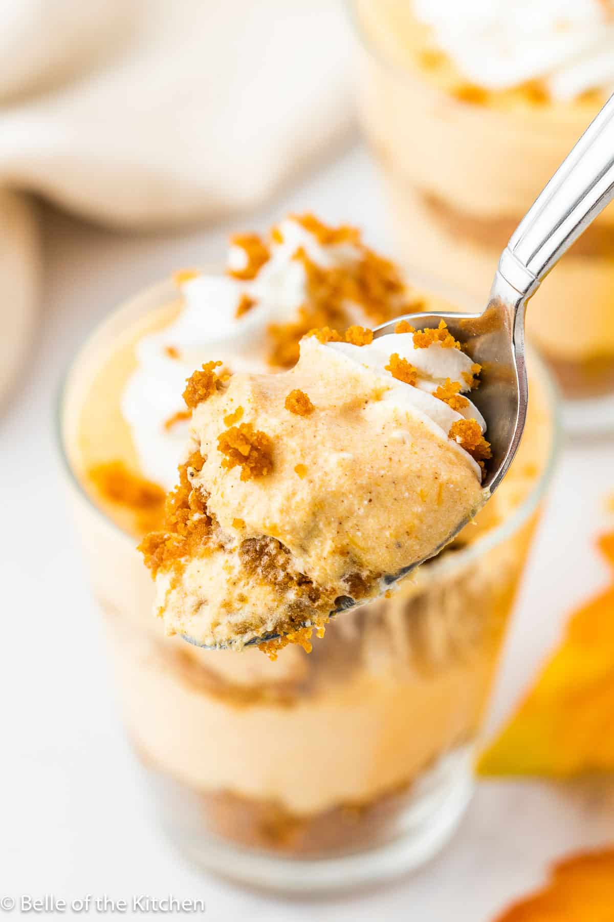 a spoon holding a scoop of pumpkin cheesecake from a pumpkin pie in a cup.