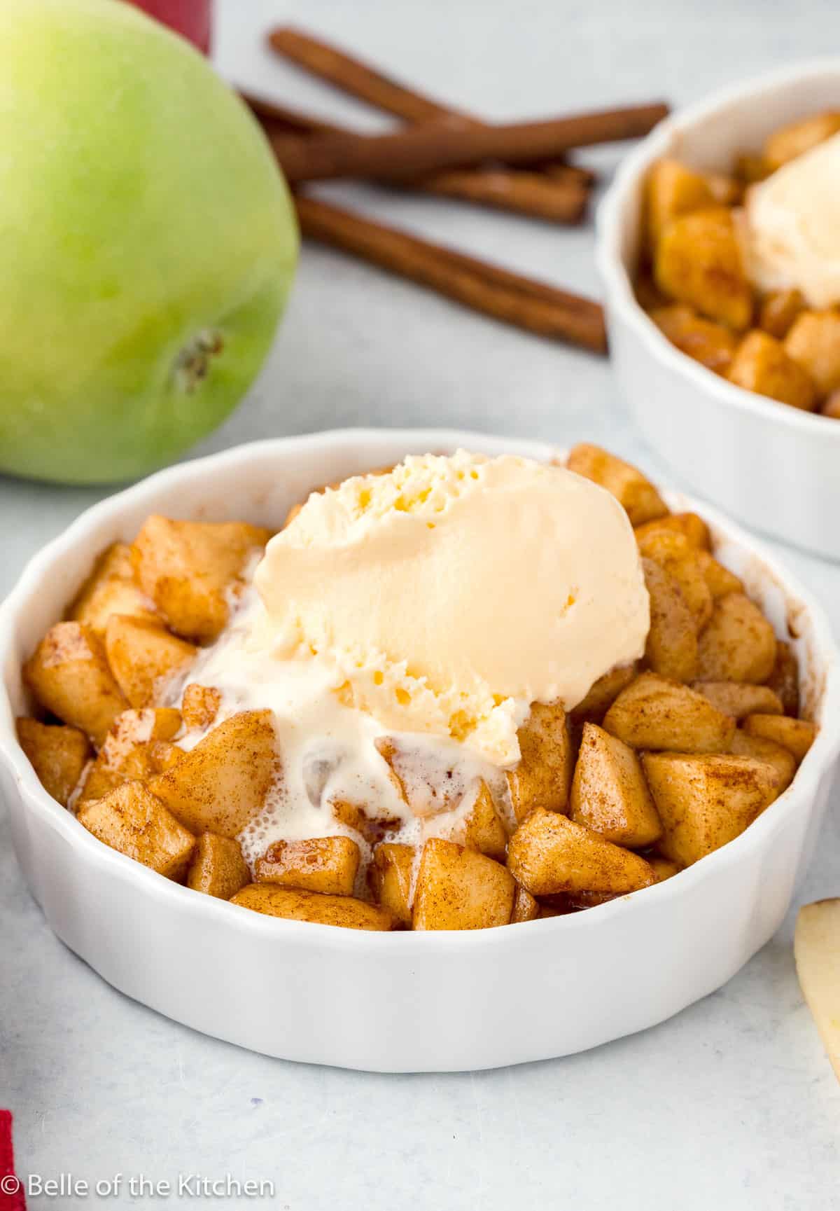 a bowl of fried apples with ice cream on top.