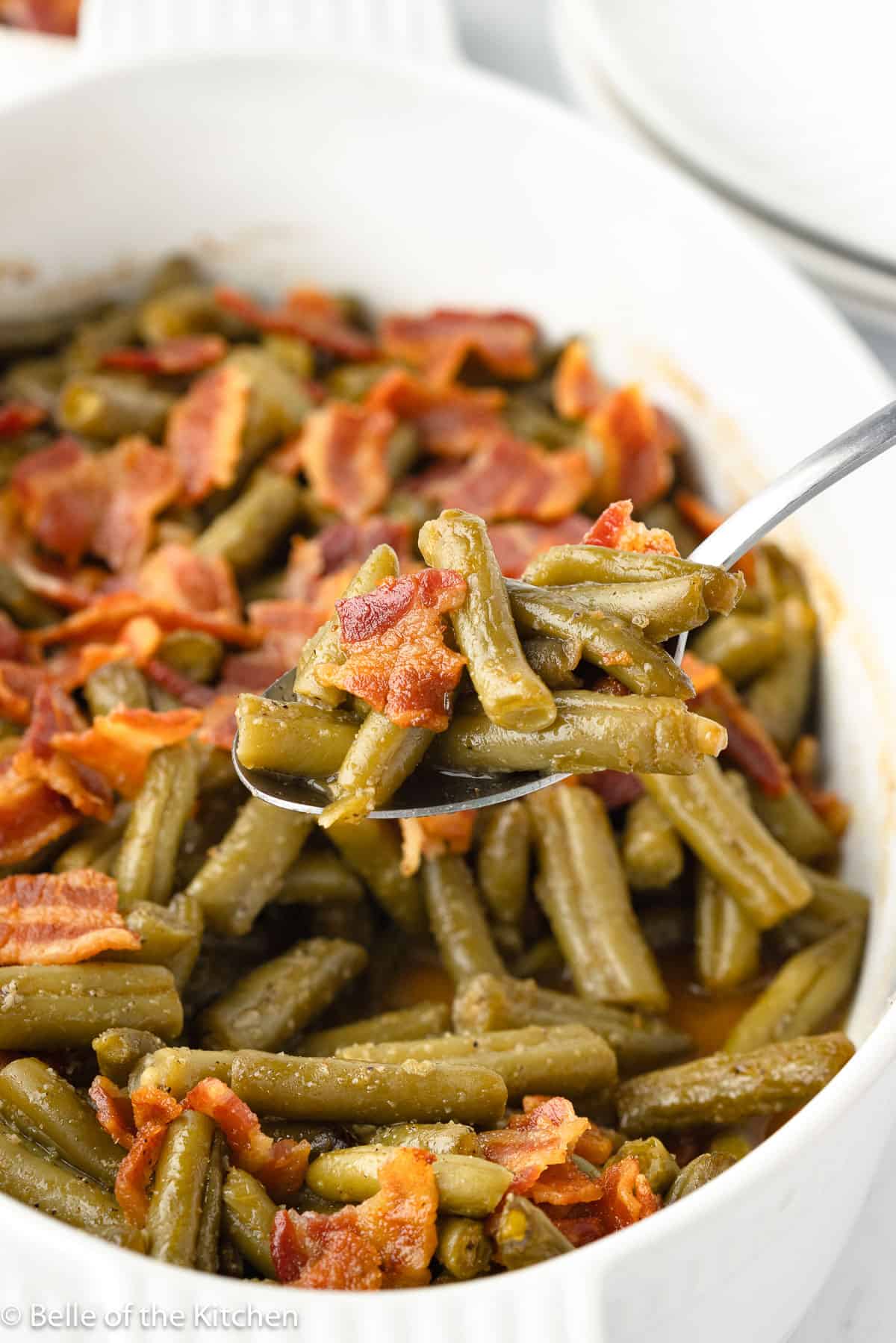a spoon scooping up smothered green beans and bacon.
