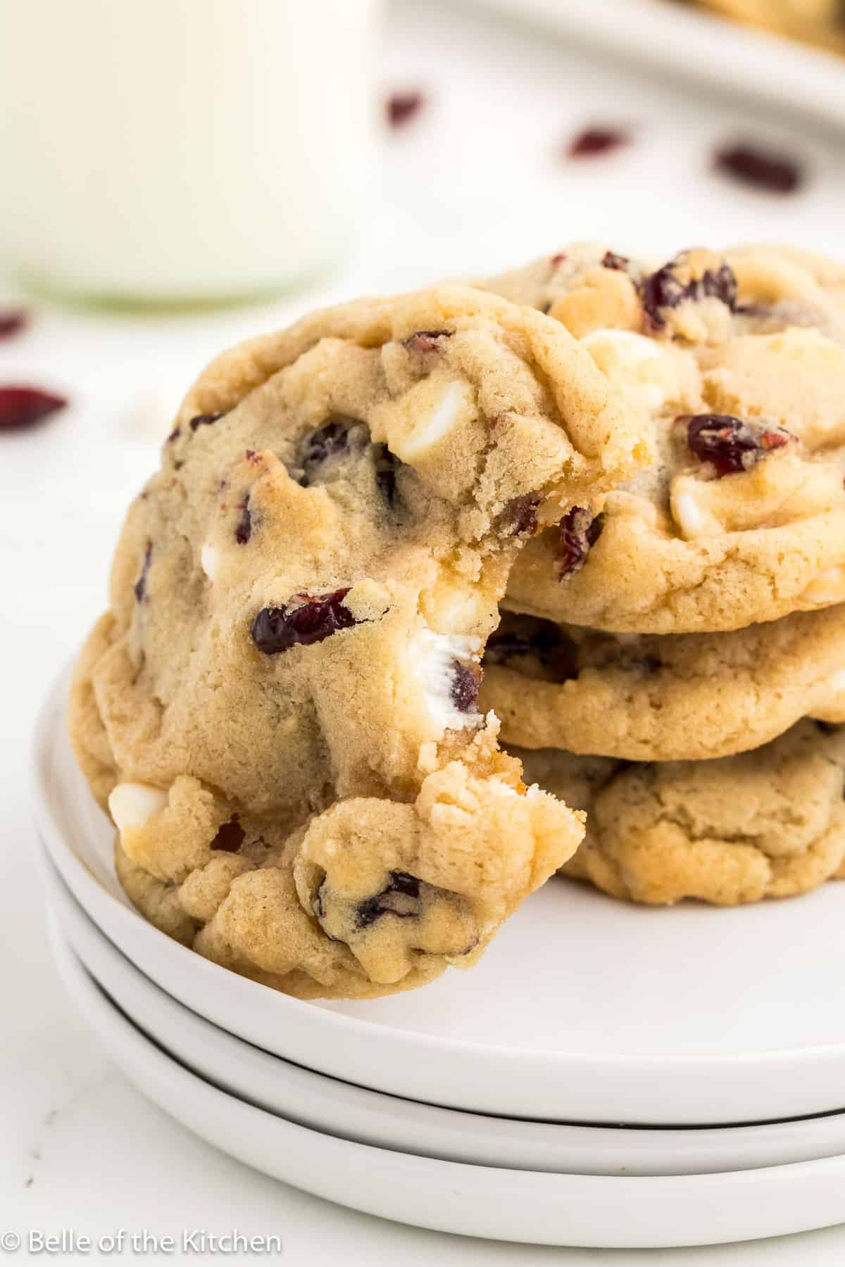a stack of cookies on a plate with one showing a bite taken out.