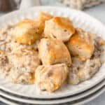 a stack of white plates with biscuits and gravy on top.