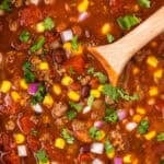 a wooden spoon stirring taco soup in a crockpot.