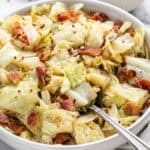 a bowl of fried cabbage and bacon on top.