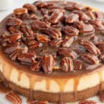 a whole cheesecake with pecan and caramel topping dripping off the edges.