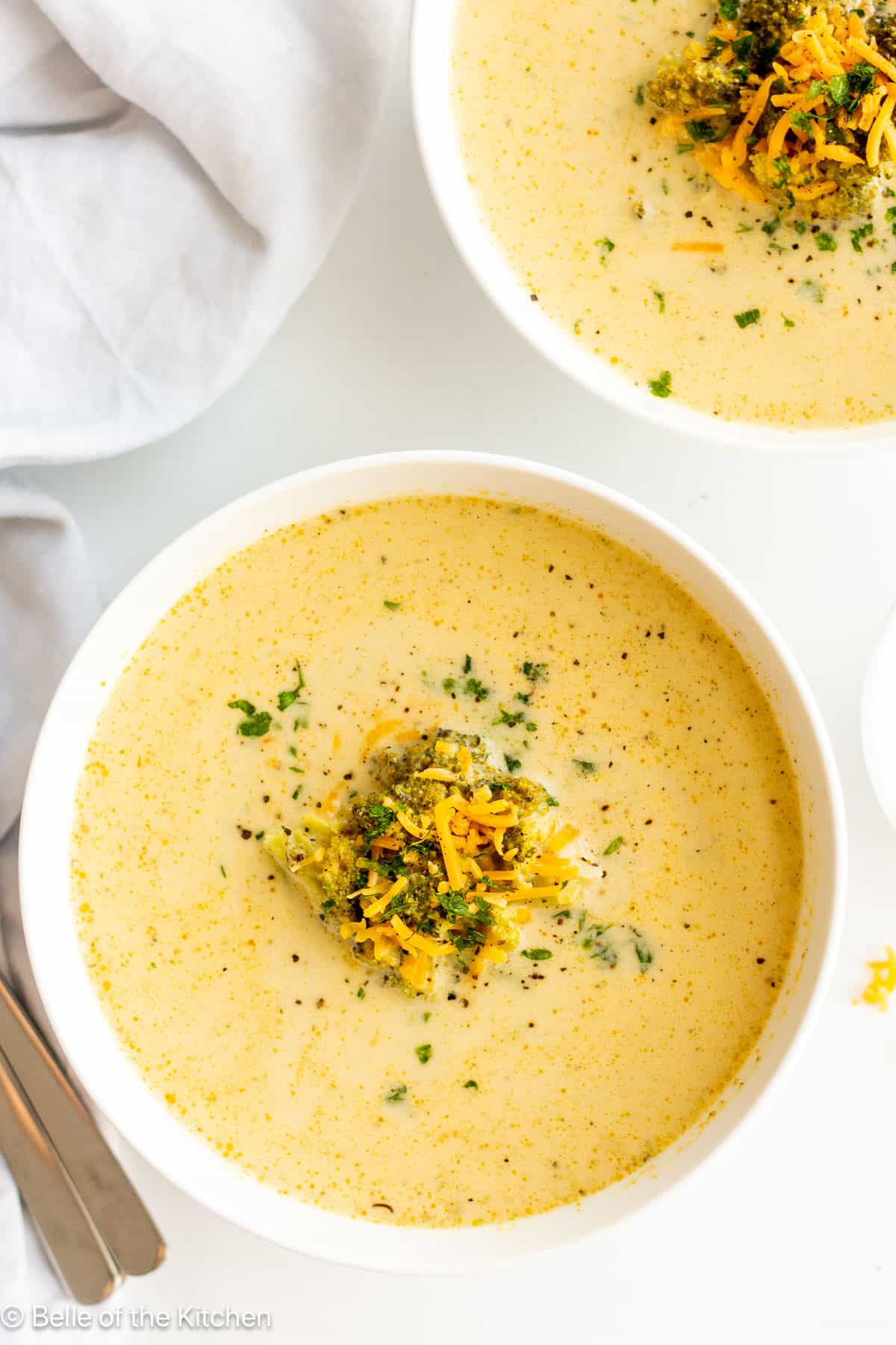 A white bowl full of broccoli cheddar soup.