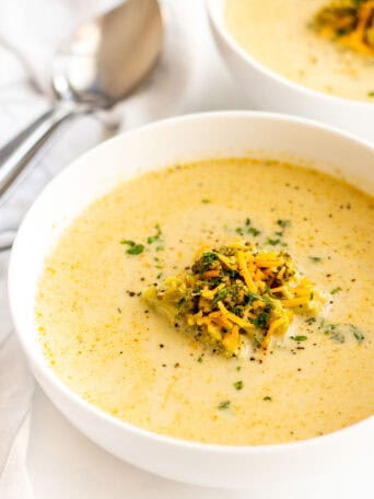A white bowl of broccoli cheddar soup.