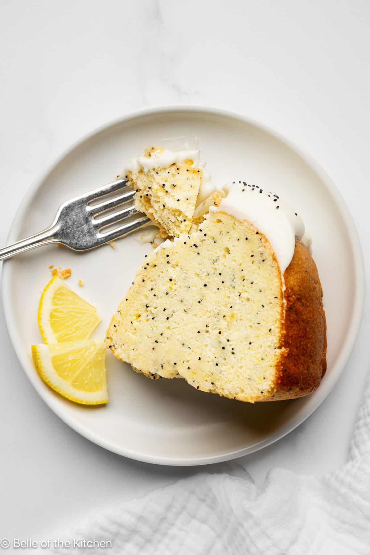 A slice of lemon cake with a fork on a plate.