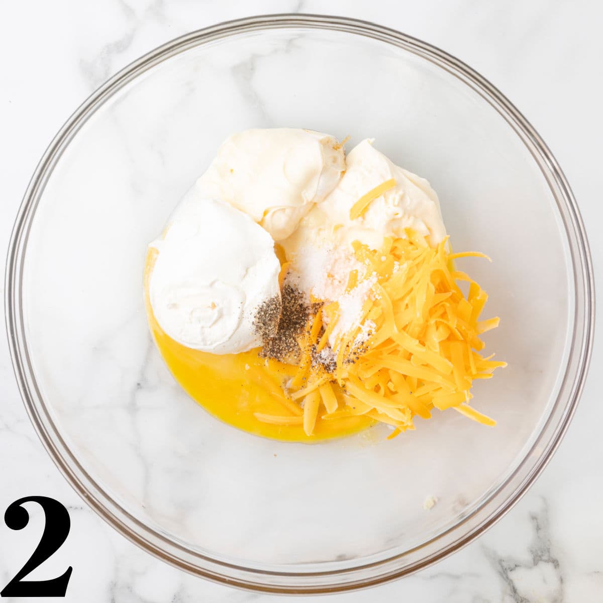 A glass bowl of mayo, sour cream, and cheese.
