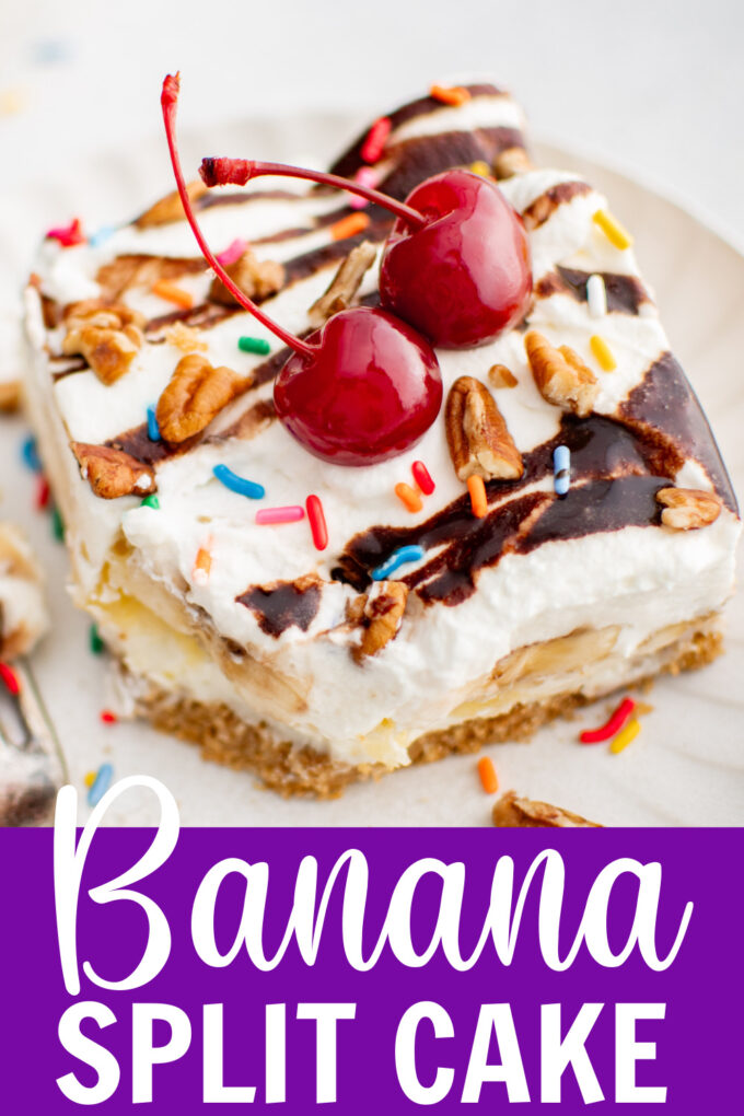 A slice of banana split cake on a plate with cherries on top next to a fork.