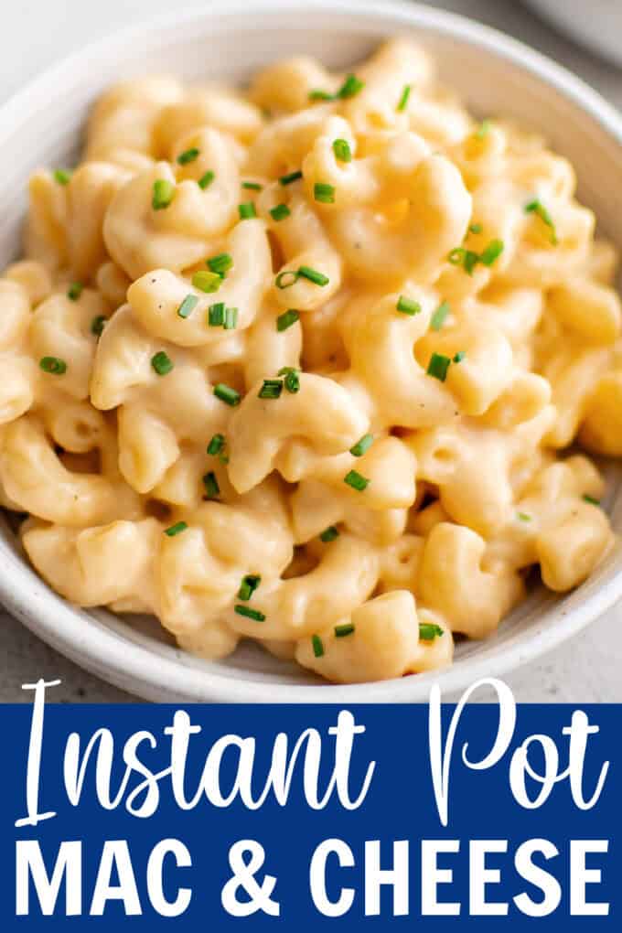A white bowl of macaroni and cheese next to a fork.