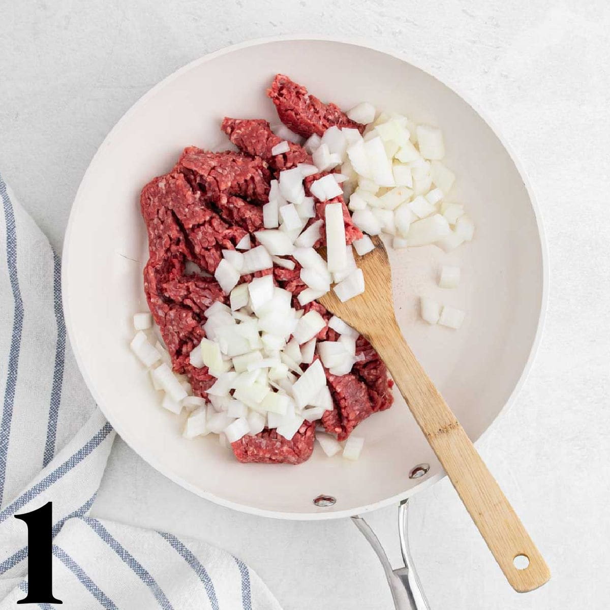 A skillet full of ground beef and chopped onions.