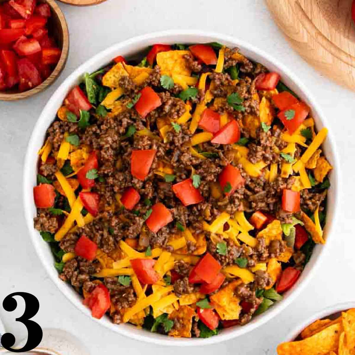 A white bowl of taco salad with Nacho Doritos.