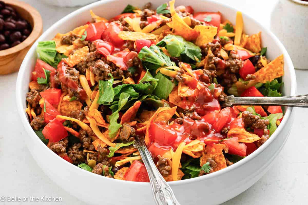 A white bowl of taco salad with Nacho Doritos.