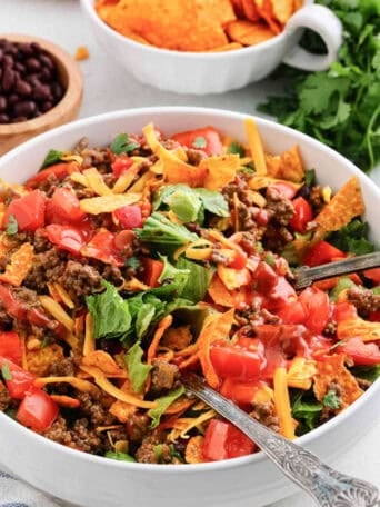 A white bowl of taco salad with Nacho Doritos.