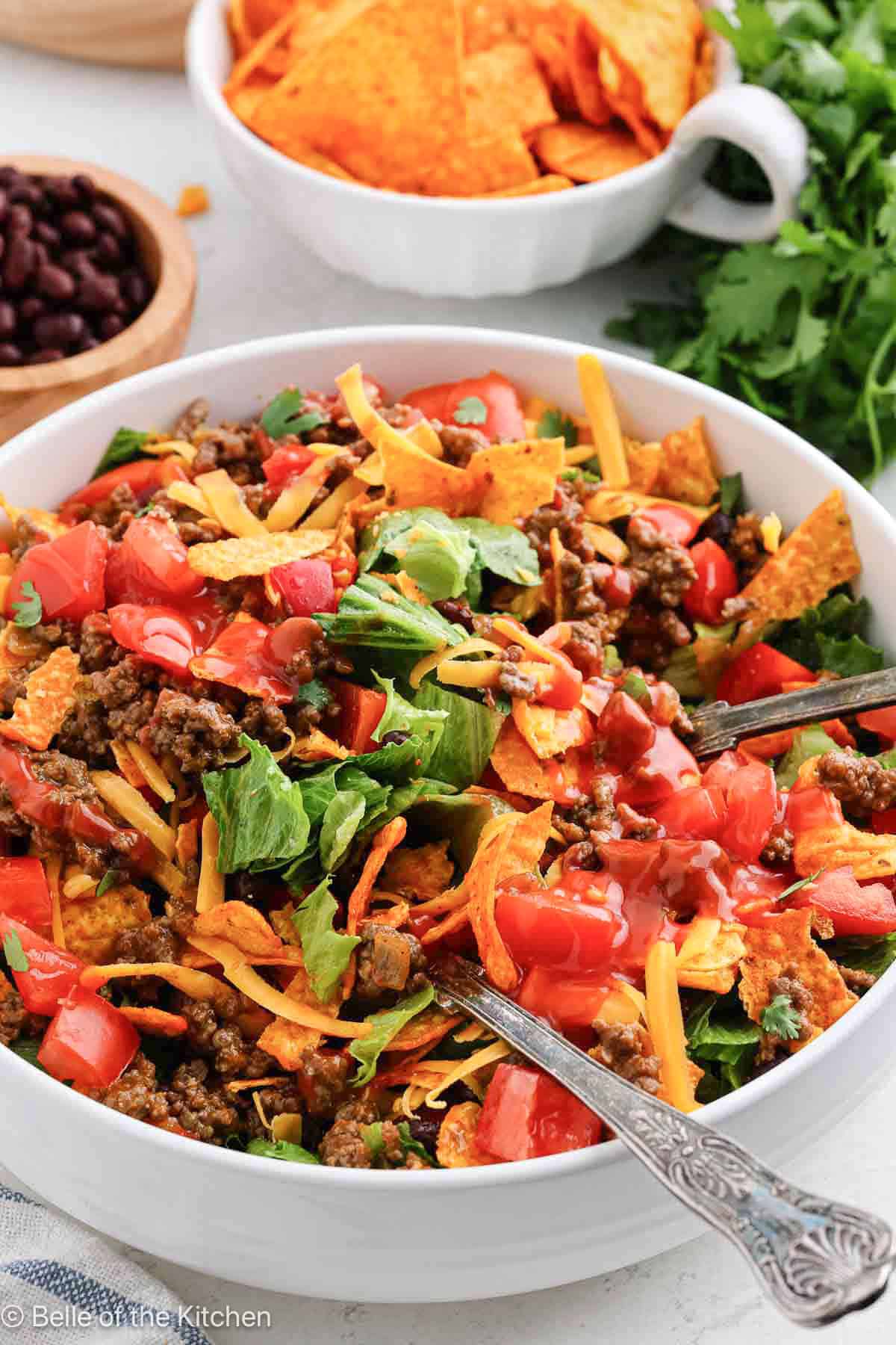 A white bowl of taco salad with Nacho Doritos.