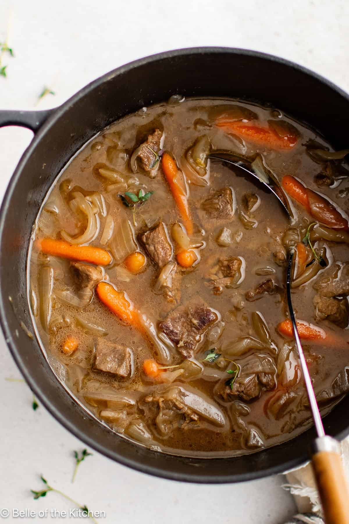 A large pot full of beef stew with carrots.