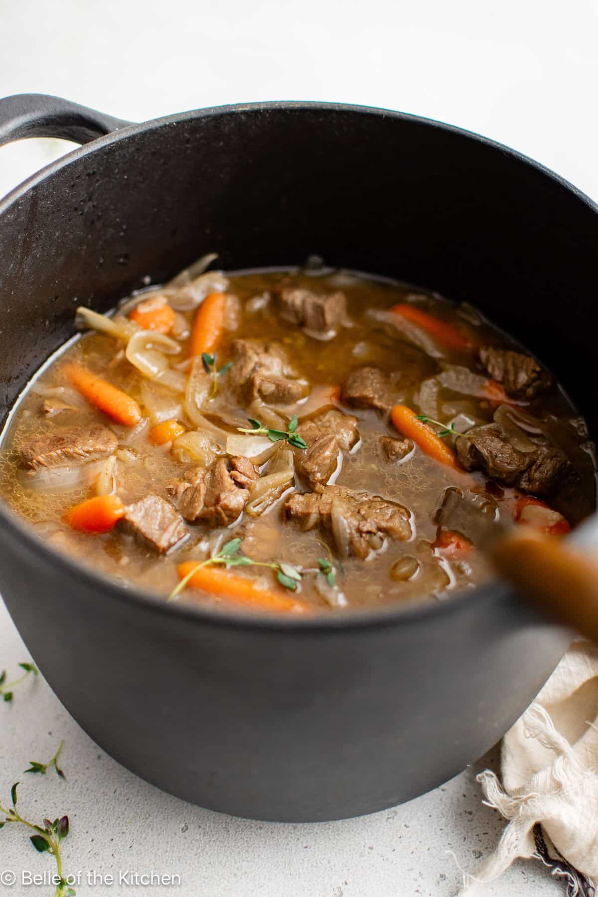 A large pot full of beef stew with carrots.