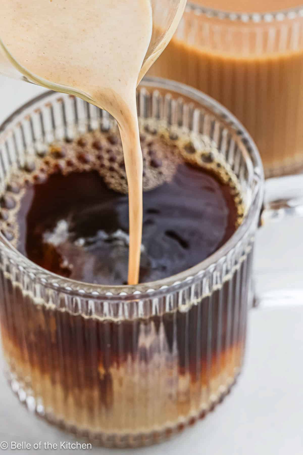 Pumpkin spice coffee creamer being poured into a mug of coffee.