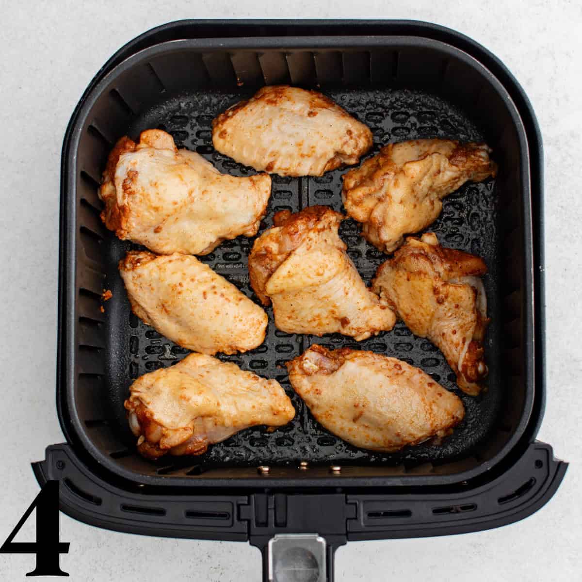 An air fryer basket full of chicken wings.